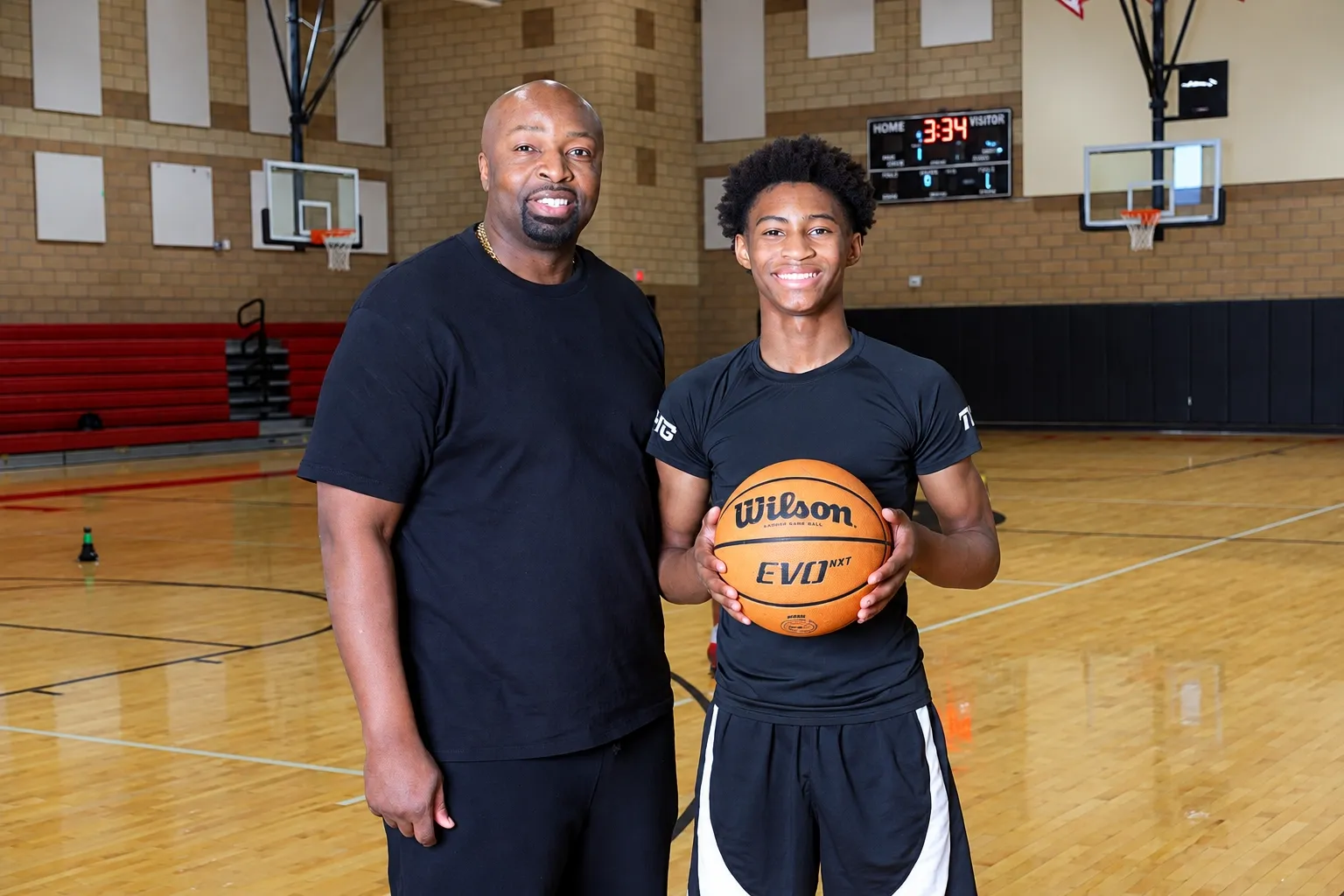 DJ Hunter and his father holding a basketball in a gym